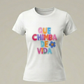 Camiseta blanca ajustada para mujer con la frase QUE CHIMBA DE VIDA estampada en el pecho con letras de colores estilo burbuja 3D y una pequeña flor azul sonriente.