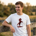 Foto lifestyle de un hombre joven sonriendo y apoyado en una cerca de madera al aire libre, vistiendo la camiseta blanca de Trnd.Ink con el estampado frontal de un caballo rojo relinchando.