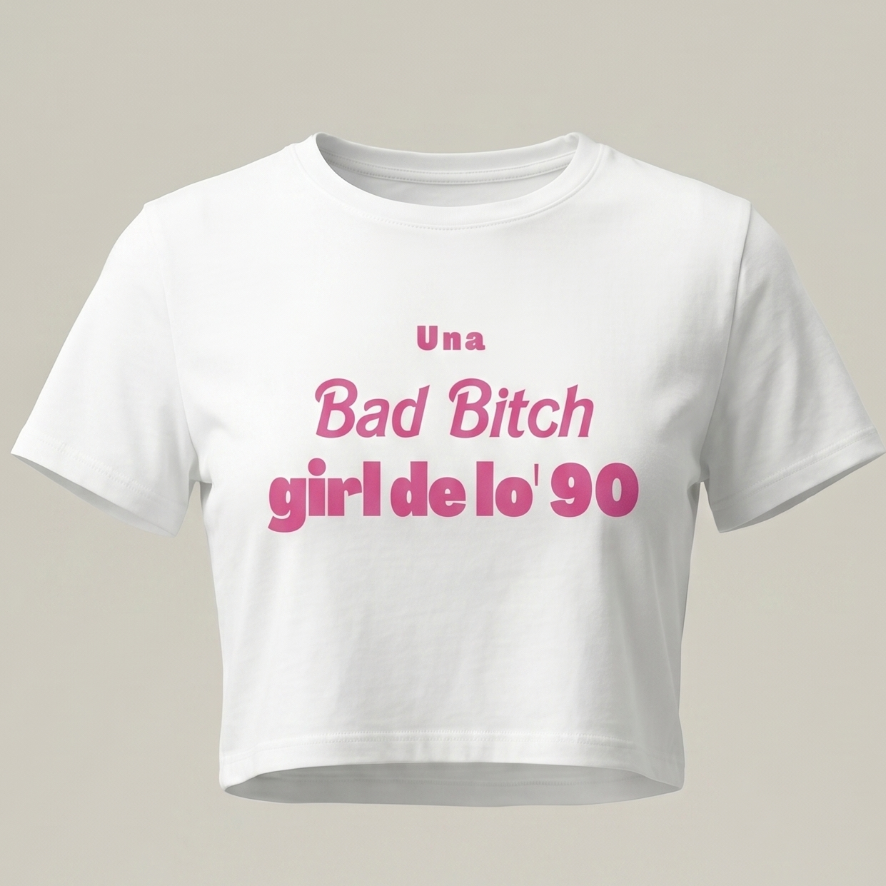 Camiseta blanca tipo crop top para mujer con estampado rosa que dice 'Una Bad Bitch Girl de lo' 90' sobre fondo neutro, estilo moda urbana retro.