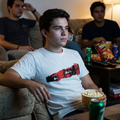 Joven luciendo una camiseta blanca con diseño gráfico de estilo anime japonés mientras disfruta de una tarde de películas, estilo urbano de Trnd.ink