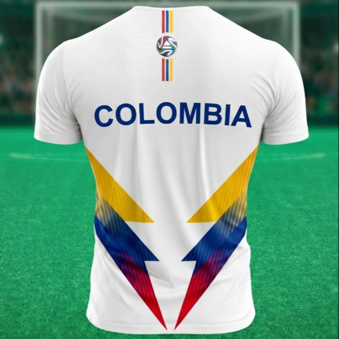 Vista posterior de una camiseta de fútbol blanca de la marca Trnd.Ink inspirada en la Selección Colombia. En la zona de la espalda resalta la palabra "COLOMBIA" estampada en letras grandes y mayúsculas de color azul oscuro. La parte inferior trasera de la prenda presenta un diseño geométrico abstracto con formas angulares en los colores de la bandera colombiana (amarillo, azul y rojo), mientras que en la parte superior central, justo debajo del cuello, se incorpora el logotipo de la marca alineado verticalm
