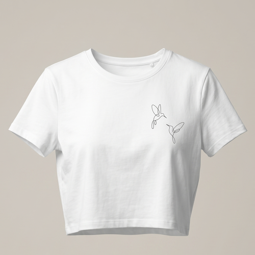 Una imagen de una camiseta corta blanca de cuello redondo y manga corta. La camiseta está colocada sobre un fondo gris claro y presenta un pequeño bordado negro en el pecho derecho que muestra dos colibríes de una línea volando uno hacia el otro. El bordado es delicado y minimalista.
