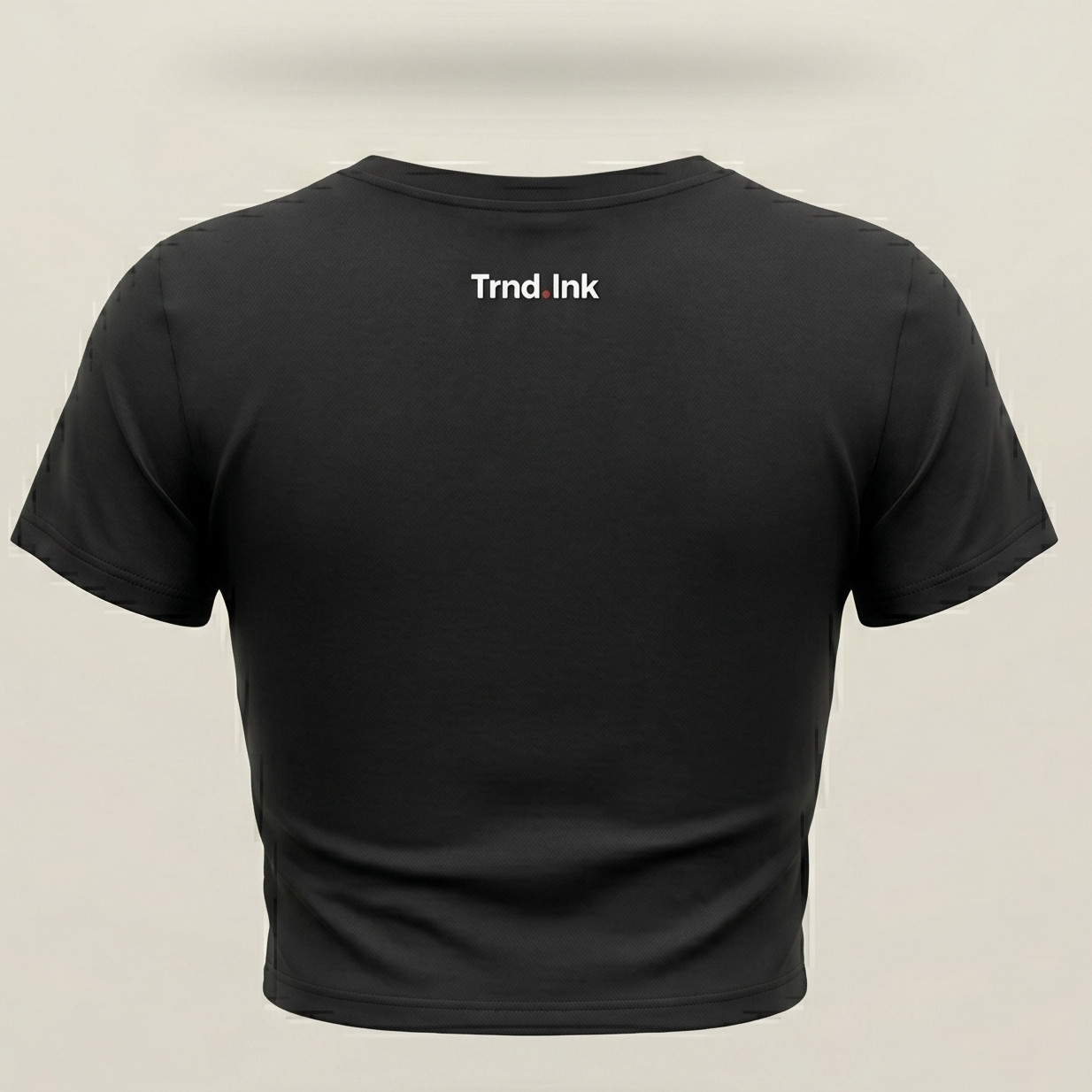 Parte trasera de una camiseta crop top negra de Trnd.Ink con logo blanco pequeño en la parte superior trasera, diseño minimalista de marca de ropa urbana.