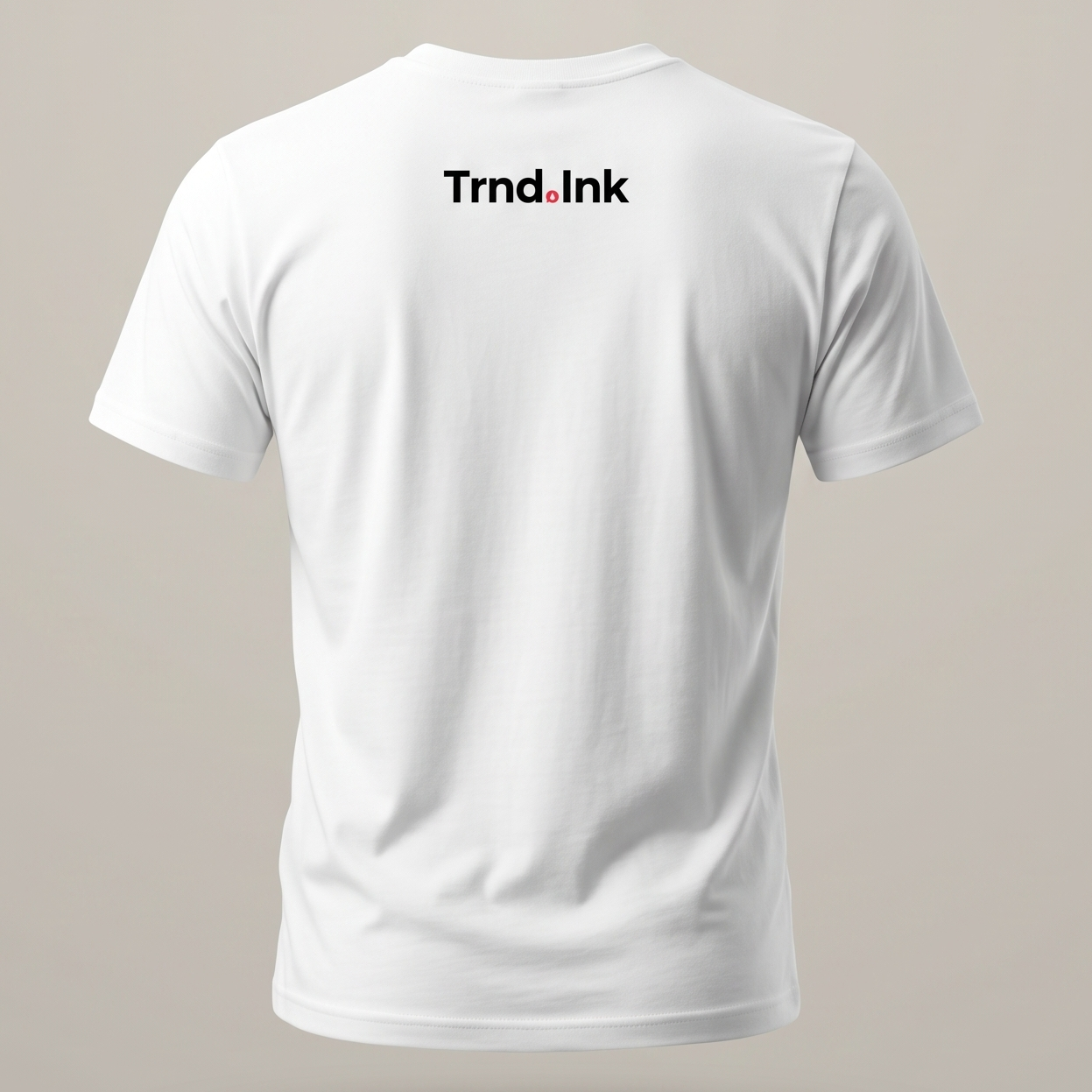 Parte trasera de una camiseta blanca de manga corta sobre un fondo gris neutro. Presenta el logotipo de Trnd.Ink centrado en la parte superior, justo debajo del cuello. La tela muestra pliegues naturales que resaltan una textura de algodón de alta calidad.