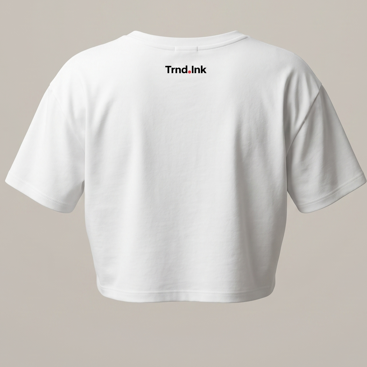 Parte posterior de una camiseta blanca tipo crop top que muestra el logotipo de Trnd.Ink en letras negras con un detalle rojo, ubicado en la parte superior central de la espalda, bajo el cuello.

