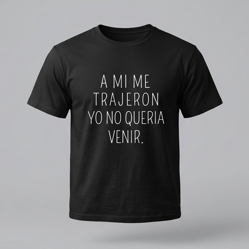 Una camiseta de algodón negra de manga corta con la frase en español 'A MI ME TRAJERON YO NO QUERIA VENIR.' impresa en la parte delantera en letras blancas finas y centradas. El fondo es de color gris claro.